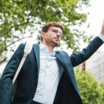 young-businessman-carrying-white-backpack-his-shoulder-hitchhiking_23-2148176143