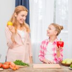 smiling-mother-daughter-holding-yellow-lemon-red-bell-pepper-hand_23-2148122668
